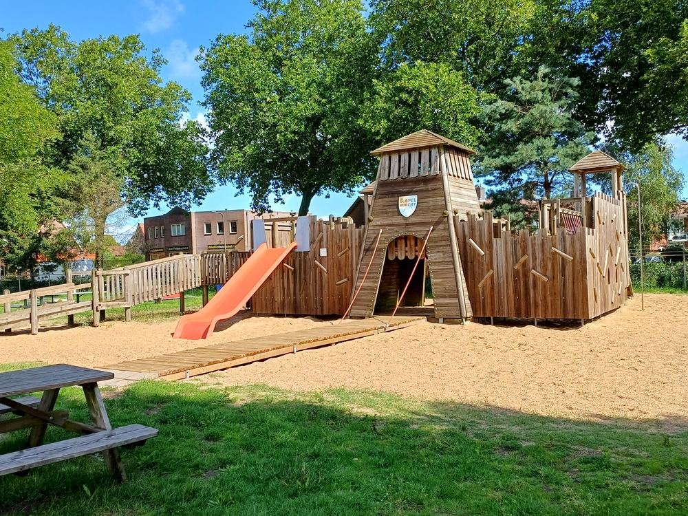 Het houten speelkasteel met glijbaan