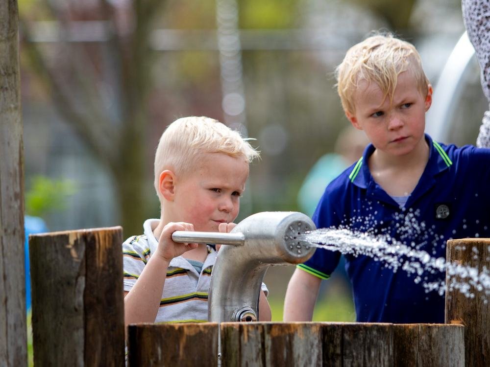 Kinderen pompen water in het waterdorp