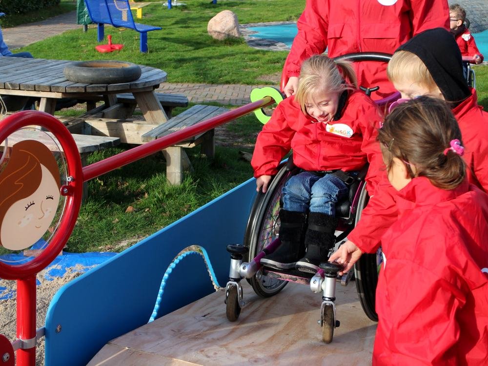 Kinderen spelen samen bij de zandtafel, ook vanuit een rolstoel